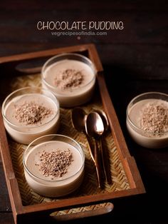 four desserts in small bowls with spoons on a tray