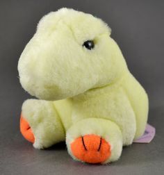 a yellow stuffed animal sitting on top of a gray table next to a white tag