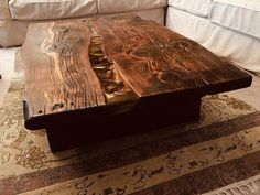 a wooden table sitting on top of a rug in front of a white sectional couch