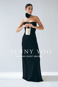 a woman in a long black dress holding a white beaded purse and posing for the camera