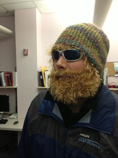 a man with a beard wearing sunglasses and a knitted hat in an office cubicle