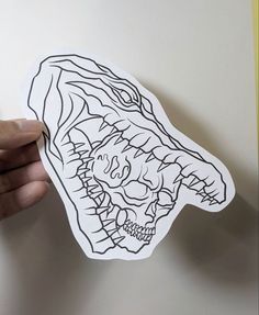 a hand holding up a sticker with an image of a monster head on it