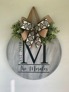 the monogrammed wreath is hung on the wall with burlocks and greenery