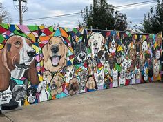 a dog mural painted on the side of a fence with dogs all over it and in different colors