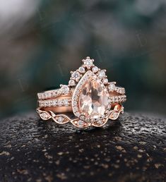 an engagement ring set with a pear shaped morganite surrounded by diamonds on top of a rock