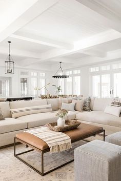 a living room filled with white furniture and lots of pillows on top of it's couches