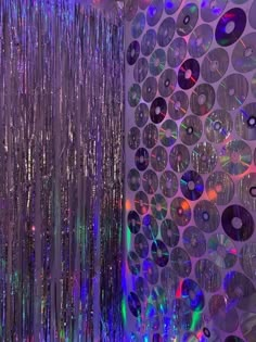 disco balls are hanging from the ceiling in front of a wall with many discs on it