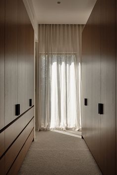 an empty hallway leading to a bedroom with white curtains