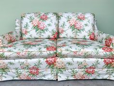 an old fashioned floral couch with red flowers on the armrests and back cushions