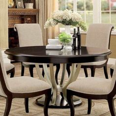 a dining room table with chairs and a vase filled with flowers on top of it