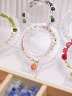 four different colored beads are on display in clear cases with wooden handles and glass lids