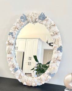 a mirror that is sitting on top of a table next to a vase with flowers in it