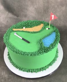 a green cake with a golf hole and flag on the top that is made to look like grass