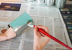 a person is painting the newspaper with a paintbrush and red handled brush on top of it