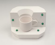 a white coffee cup and saucer sitting on top of a stack of cubes