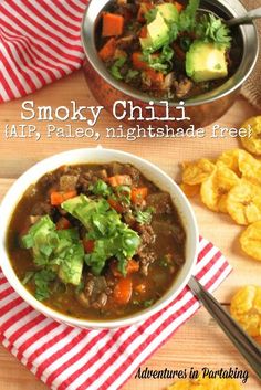 two bowls filled with soup sitting on top of a wooden table next to potato chips