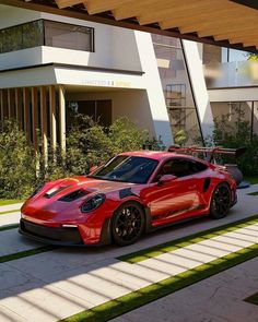 a red sports car parked in front of a modern building with grass and trees around it