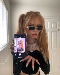 a woman taking a selfie with her cell phone in front of her face and wearing sunglasses