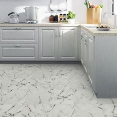 a kitchen with white cabinets and marble flooring