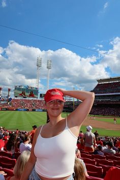 a woman in a white tank top and red hat at a baseball game with fans