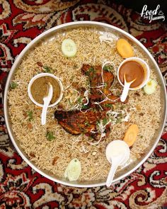 a platter filled with rice, meat and sauces on top of a rug