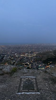 an empty bench on top of a hill overlooking a city