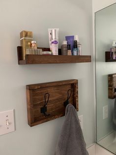 two wooden shelves holding personal care items in a bathroom with a towel hanging on the wall