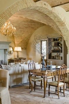 a living room filled with furniture and a chandelier hanging from the ceiling over a fire place