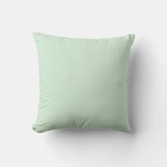 a light green pillow sitting on top of a white wall