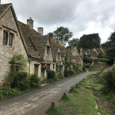 an old village with stone buildings and green plants on the side of the road in front of it