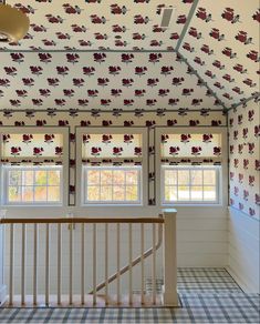 an empty room with two windows and wallpaper on the ceiling is decorated with red flowers