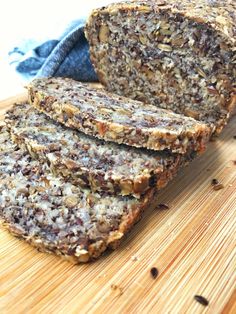 sliced loaf of granola bread sitting on top of a wooden cutting board