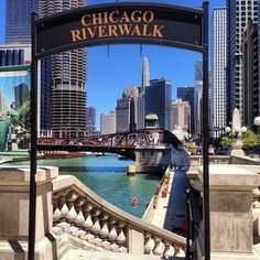 the chicago riverwalk sign is in front of some tall buildings and a body of water