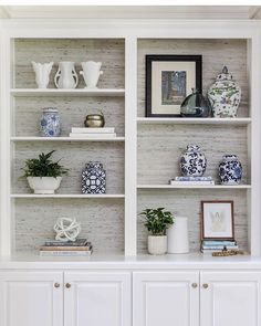 a white bookcase with blue and white vases on it