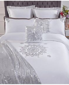 a white bed with silver sequins and pillows