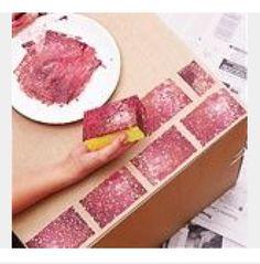 a person holding a piece of meat on top of a cardboard box next to a plate