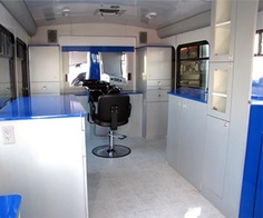 the inside of a bus with blue counter tops and white cabinets on each side of the room