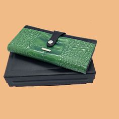 Make a statement with this luxurious green leather wallet for women. Crafted with a striking alligator pattern in green and black, this designer wallet is a must-have for those who appreciate quality and style. Featuring ample storage space, this wallet has 6 card slots, 2 ID windows, and 2 compartments, as well as separate pockets for coins and bills. It measures 8.50 /4.50 inches (22cm / 11cm) and weighs an average of 230 grams (0.50 pounds), making it both practical and comfortable to carry. Luxury Green Rectangular Wallets, Luxury Green Wallet With Coin Pocket, Alligator Pattern, Luxury Green, Designer Wallet, Wallet For Women, 50 Pounds, Wallet Pattern, Clip Wallet