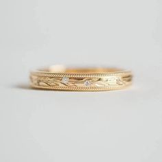 a gold wedding band with three diamonds on the inside and outside, set in 18k yellow gold