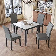 a dining room table with four chairs and a white marble top in front of a window