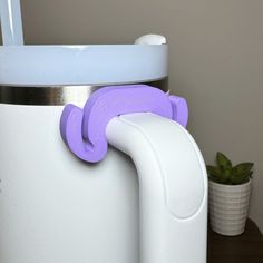 a purple handle is attached to the side of a white coffee pot