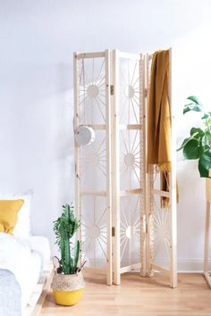 a white room divider sitting on top of a hard wood floor next to a potted plant