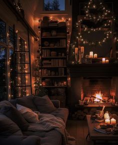 a living room filled with lots of furniture and lit candles in front of a fire place