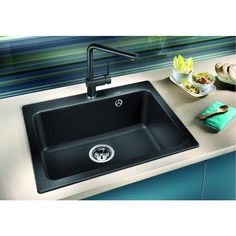 a black kitchen sink sitting on top of a counter next to a plate of food