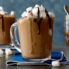 two mugs filled with hot chocolate and marshmallows on top of a table