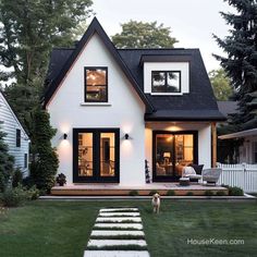 a white house with black shingles and steps leading up to the front door area