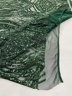 green and silver sequins are on the ground next to a piece of cloth