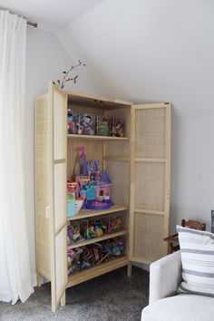 a book shelf with toys in it next to a couch