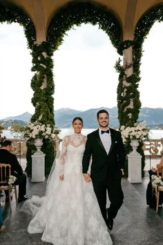 a bride and groom are walking down the aisle at their wedding in front of an archway