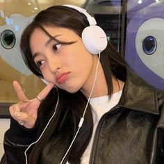 a young woman wearing headphones making the peace sign